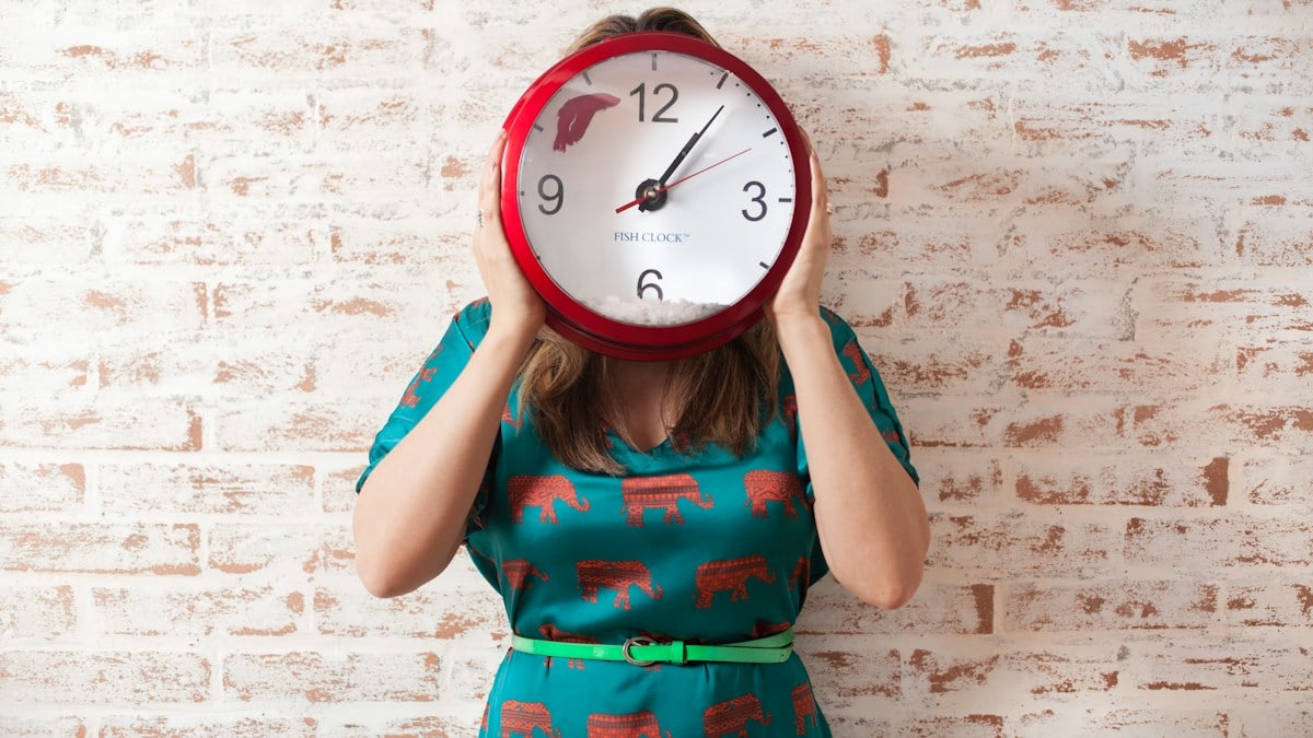 woman covering face using wall clock