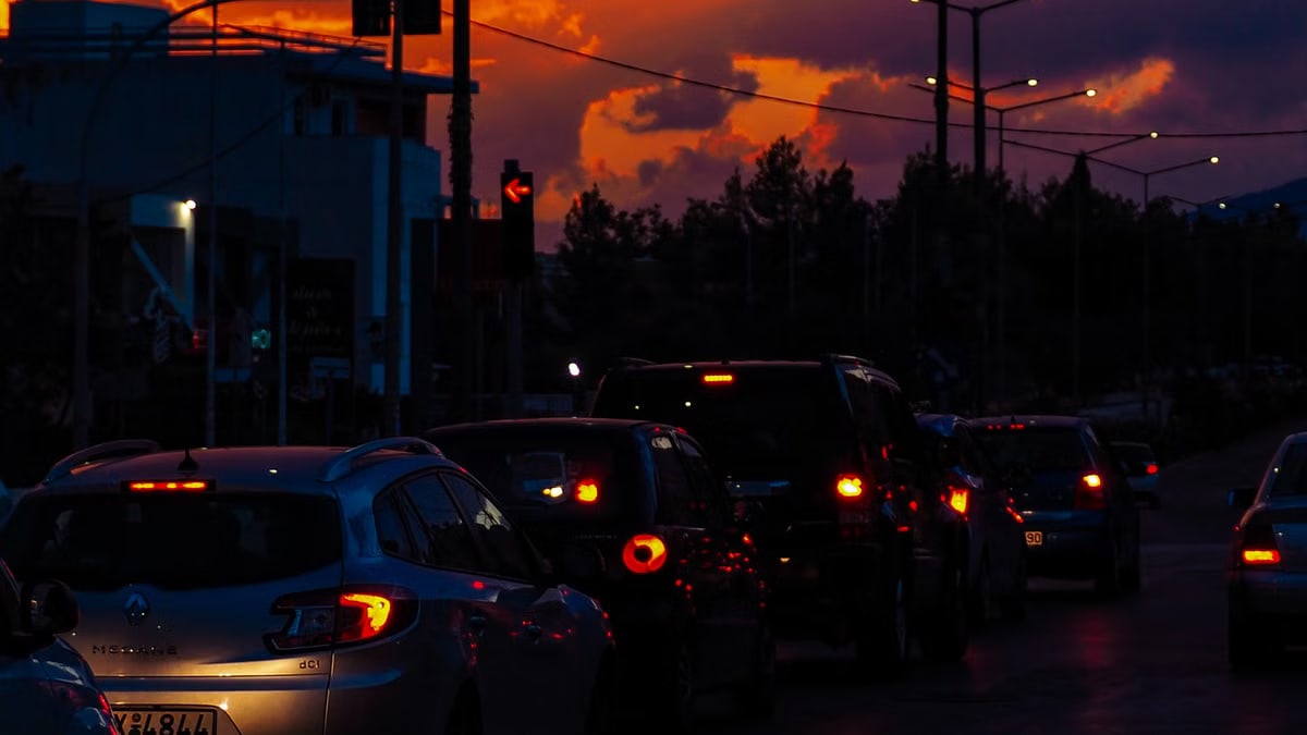 Cars lined up on a street at dusk with a vibrant sunset sky creating a dramatic silhouette scene.